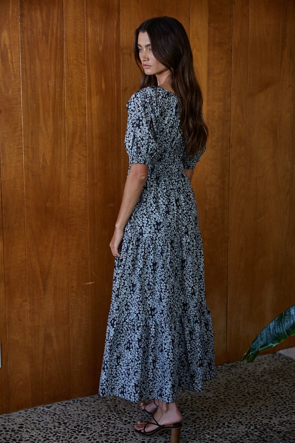 Woman wearing a black and blue maxi dress against a wooden background