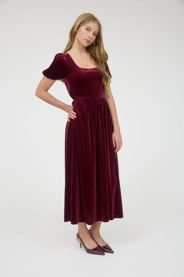 Woman wearing a burgundy velvet dress on a white background