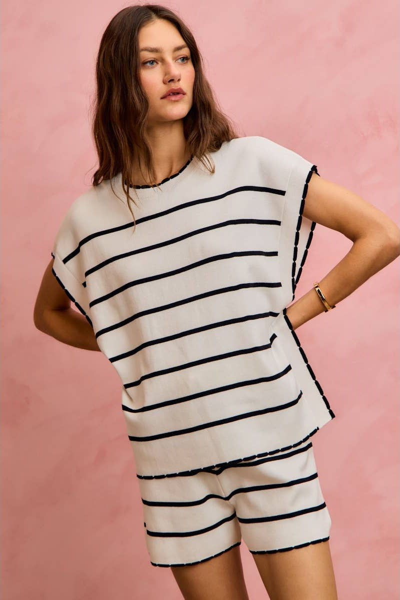 Woman wearing a black and white striped outfit against a pink background