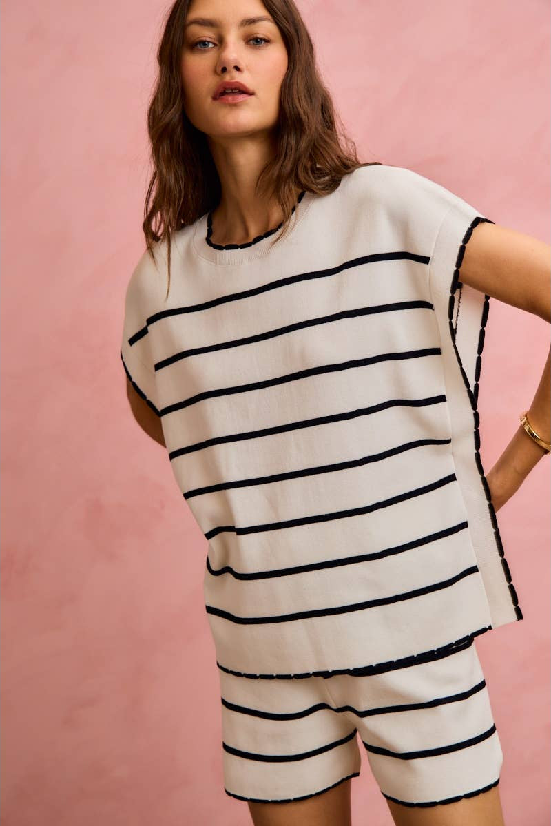 Woman wearing a white and black striped outfit against a pink background