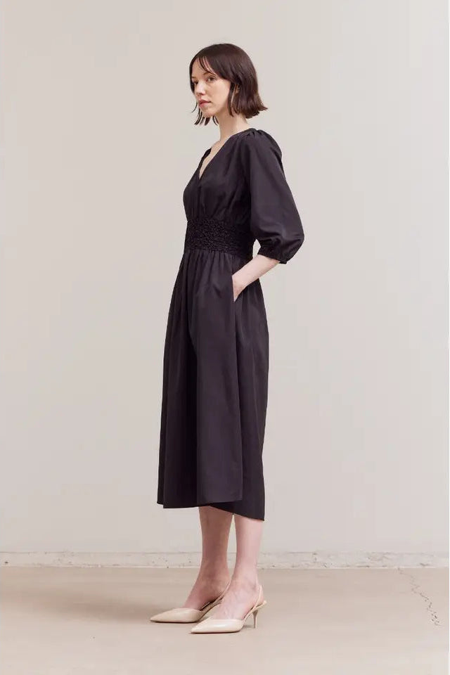 Woman wearing a black dress against a plain background