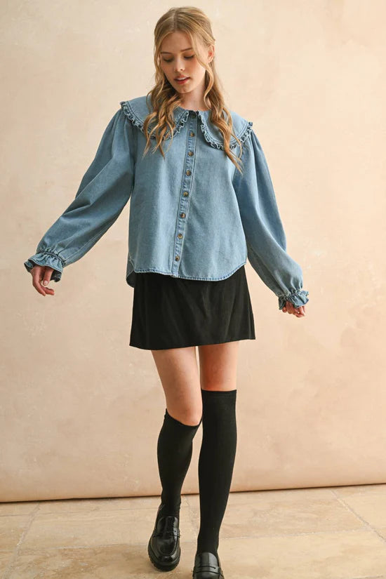 Woman wearing a denim shirt, black skirt, and knee-high socks against a beige background