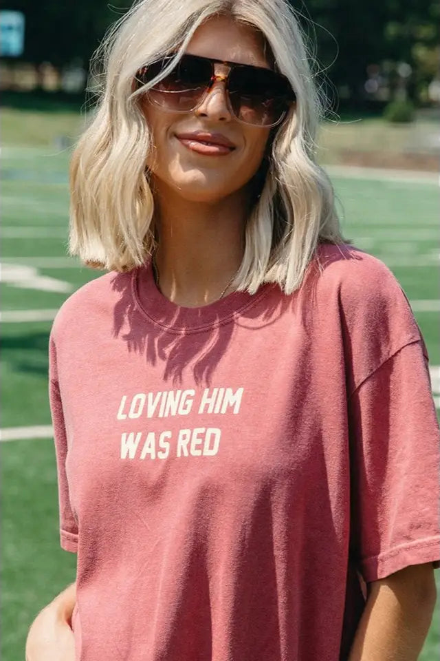 Person wearing a pink t-shirt with text on a grassy field