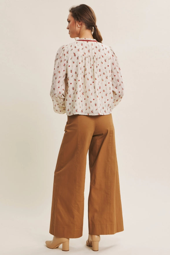 Woman wearing a floral blouse and brown pants on a white background