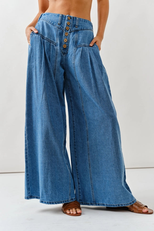 Wide-leg blue jeans worn by a person on a white background