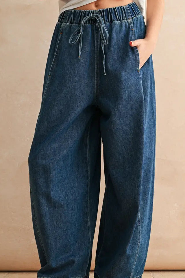 Blue denim pants worn by a person on a beige background