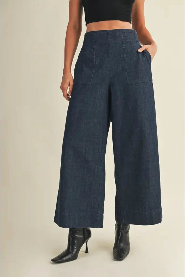 Person wearing dark blue wide-leg pants on a beige background