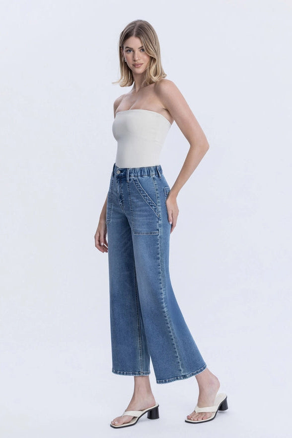 Woman wearing a strapless top and wide-leg jeans on a white background