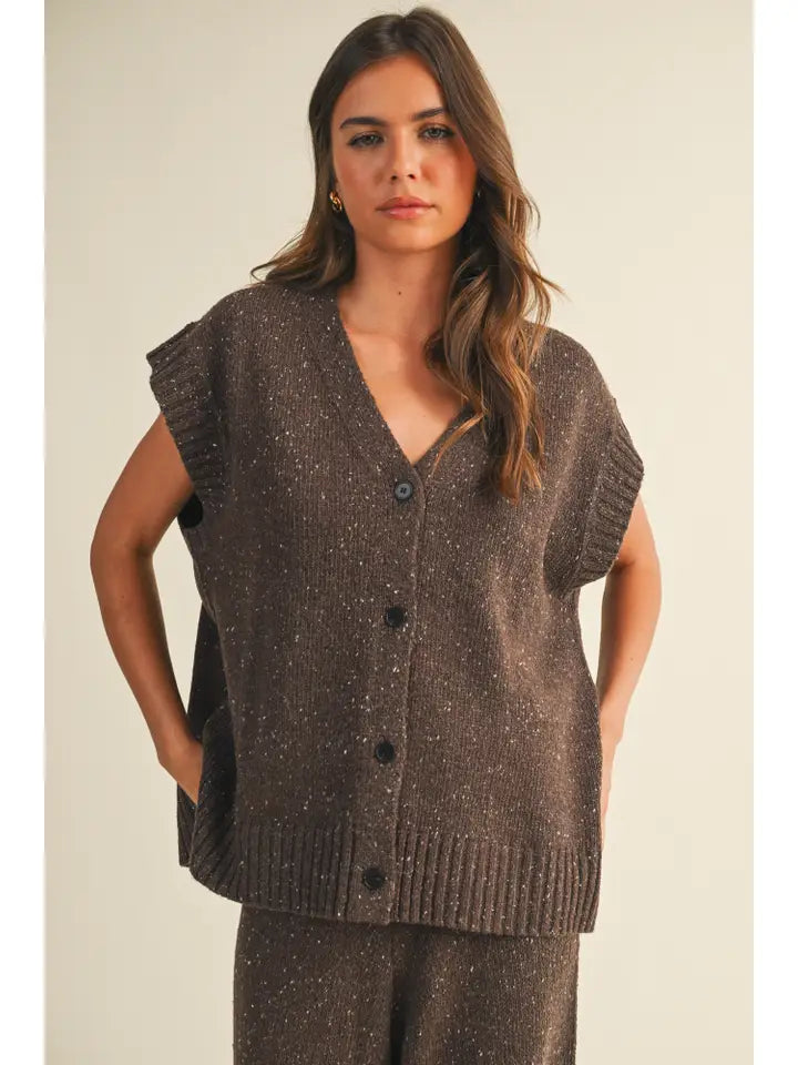 Woman wearing a brown knitted vest against a plain background