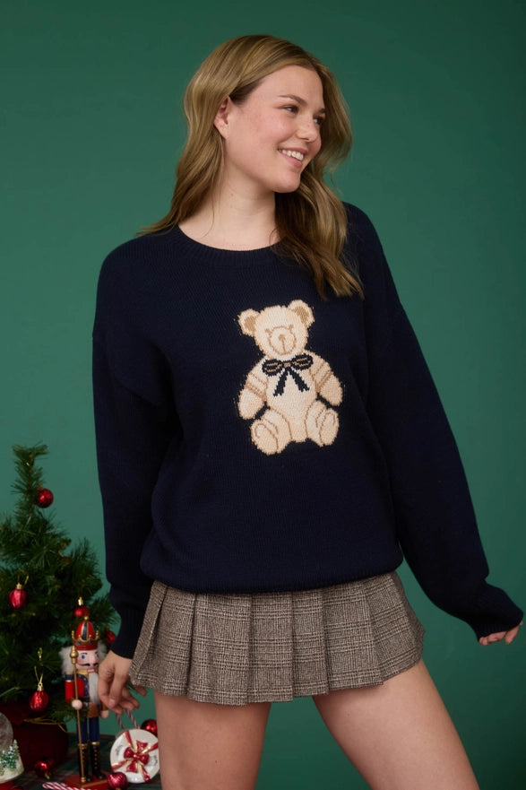 Woman wearing a navy sweater with a teddy bear design against a green background