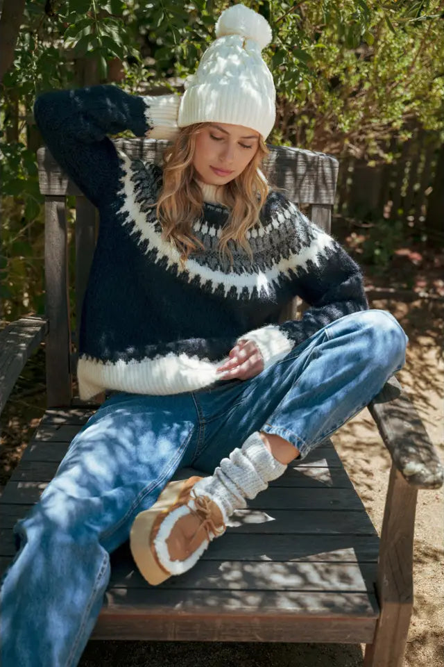 Woman sitting outdoors wearing a patterned sweater and jeans