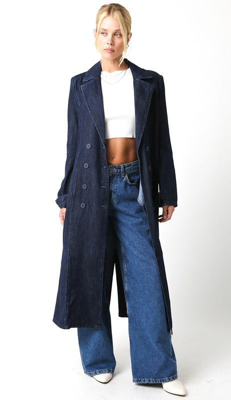 Woman wearing a long dark coat and blue jeans on a white background