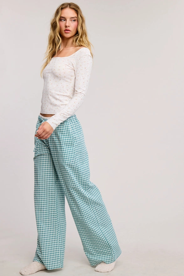Woman wearing a white top and green checkered pants on a plain background