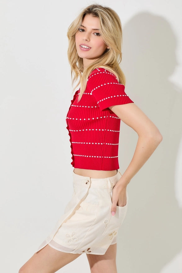 Woman wearing a red striped shirt and white shorts on a plain background