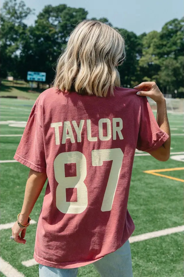 Person wearing a red jersey with 'Taylor 87' on a sports field