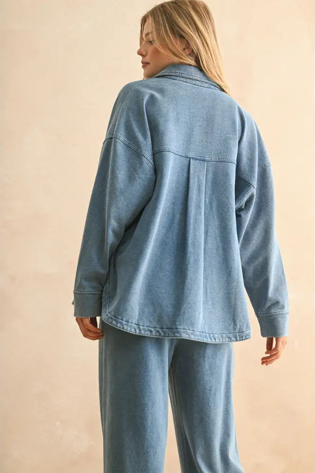 Person wearing a blue denim jacket and pants on a beige background
