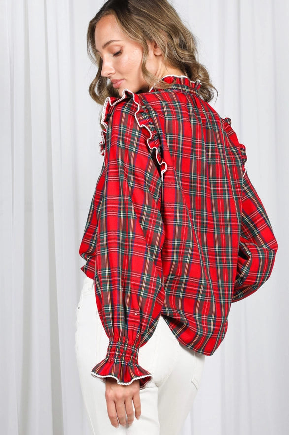 Woman wearing a red plaid shirt with ruffled details against a white background