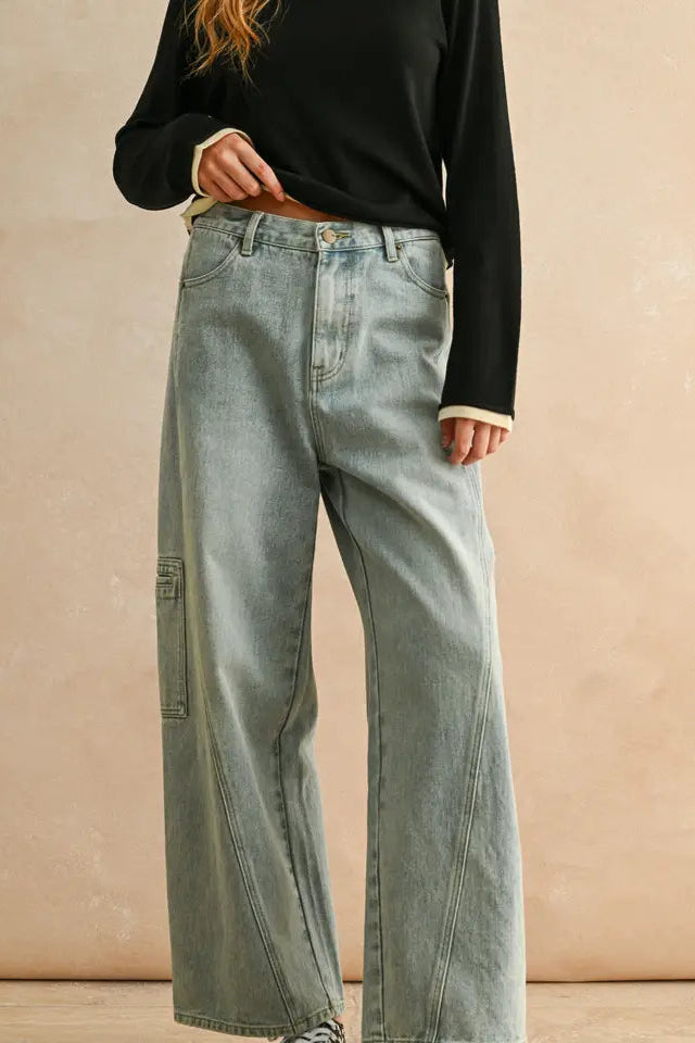 Person wearing light blue jeans and a black top against a beige background