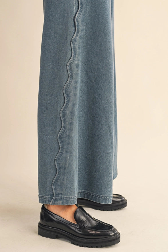 Blue jeans with a decorative edge and black shoes on a beige background