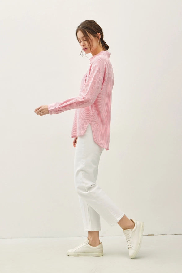 Woman wearing a pink shirt and white pants on a white background