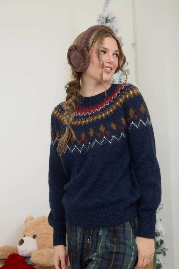 Woman wearing a patterned navy sweater with plaid pants indoors.