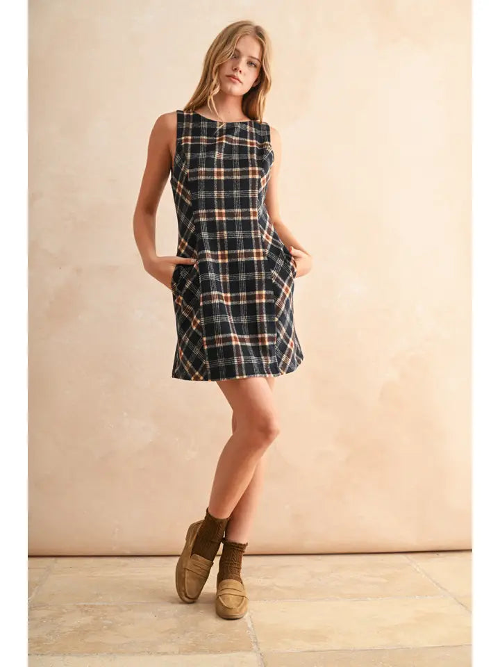 Woman wearing a plaid dress with brown shoes against a beige background