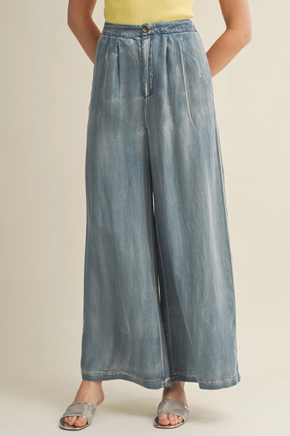 Person wearing wide-leg blue jeans on a beige background