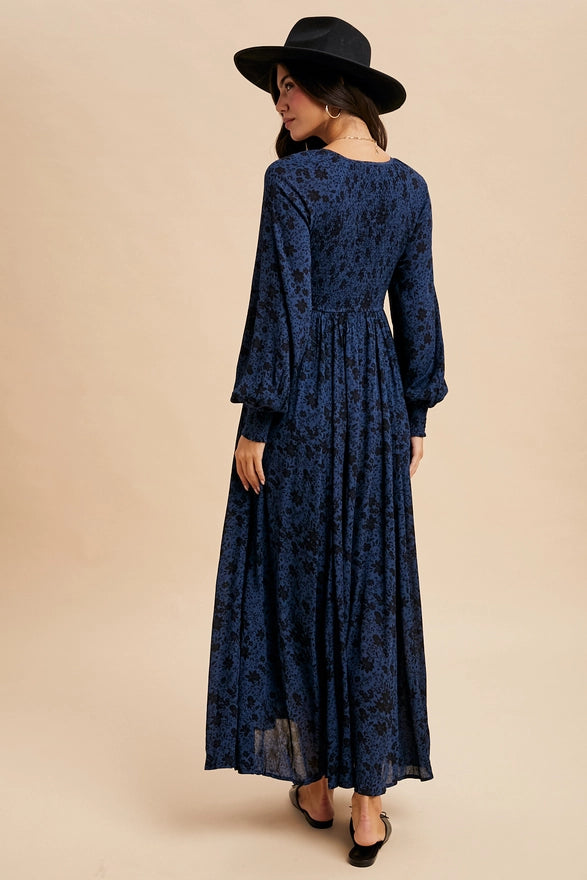 Woman wearing an indigo floral maxi dress on plain background.