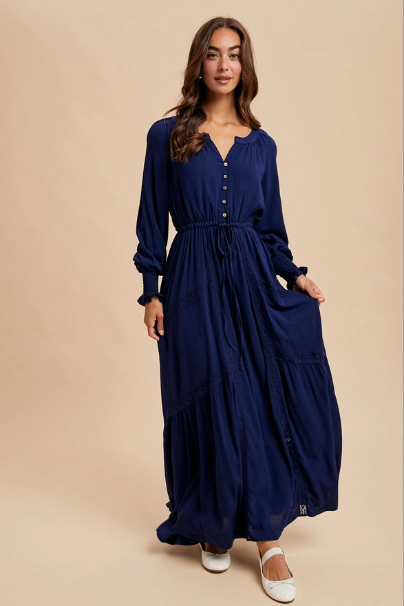 Woman wearing a navy color maxi dress with long sleeves on plain background