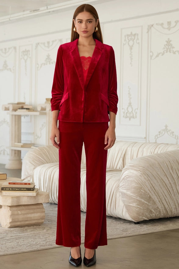 Woman wearing a red suit in an elegant room with white walls and furniture.