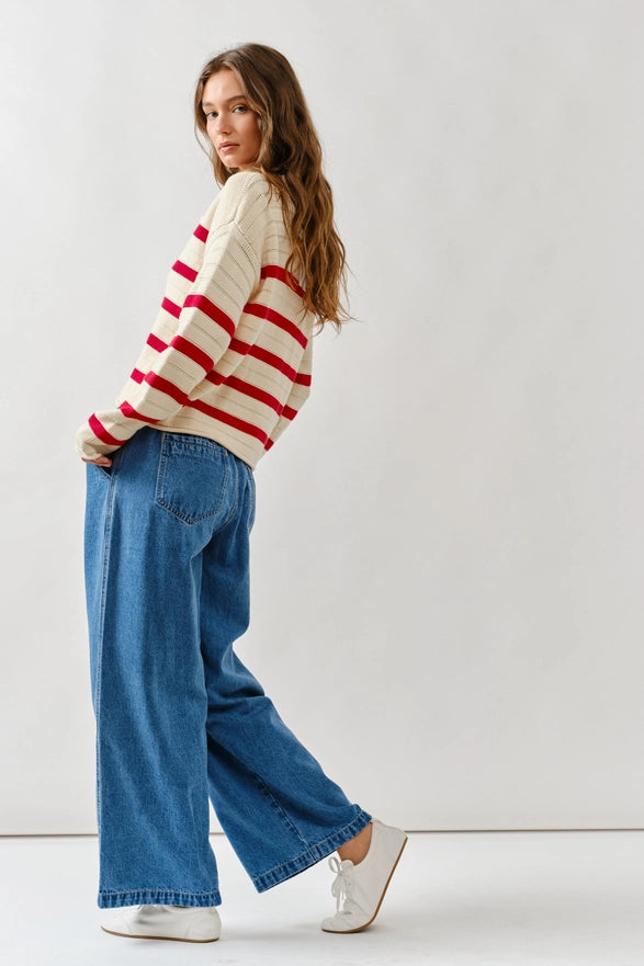 Woman wearing a striped sweater and blue jeans against a white background