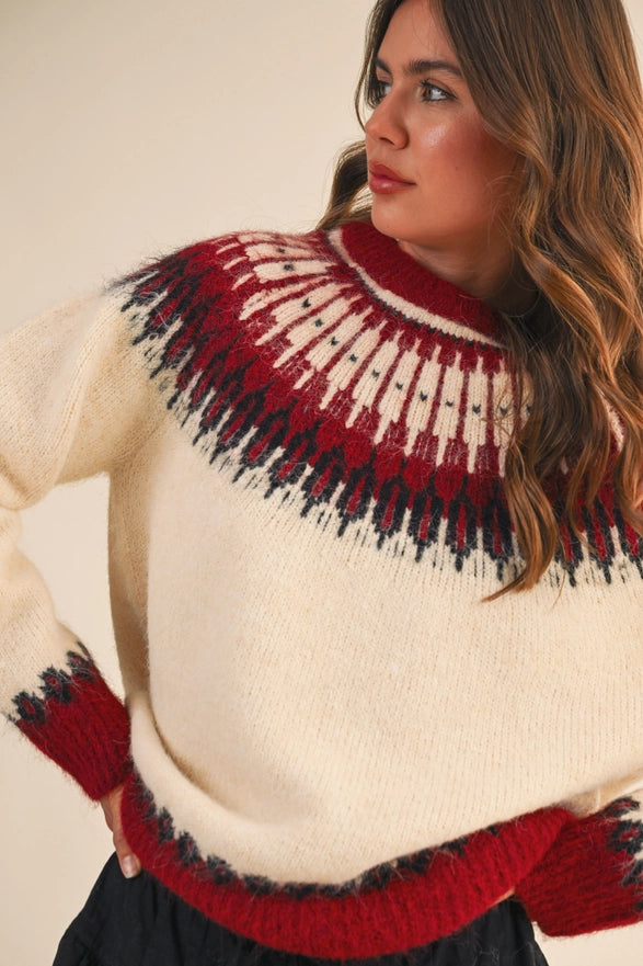 Woman wearing a cream sweater with red and black pattern