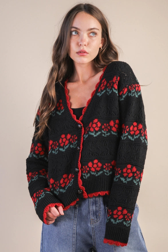 Woman wearing a black cardigan with red and green floral patterns on a beige background