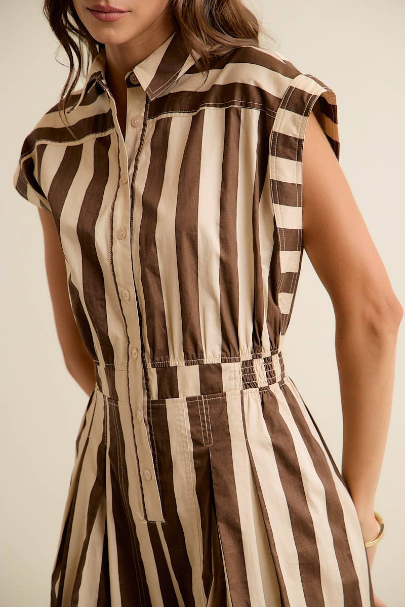 Woman wearing a brown and beige striped dress against a neutral background