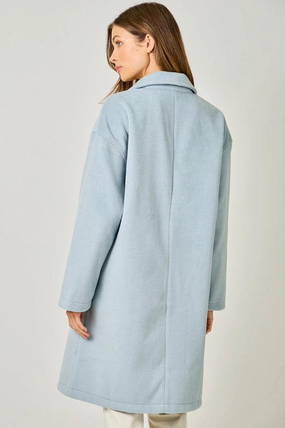 Woman wearing a light blue coat against a plain background