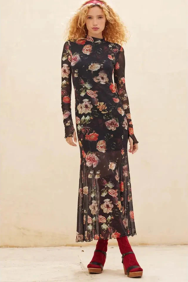 Woman wearing a floral dress with long sleeves against a plain background