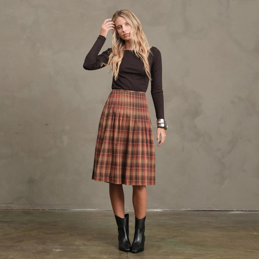 Woman wearing a plaid skirt and black top against a plain background