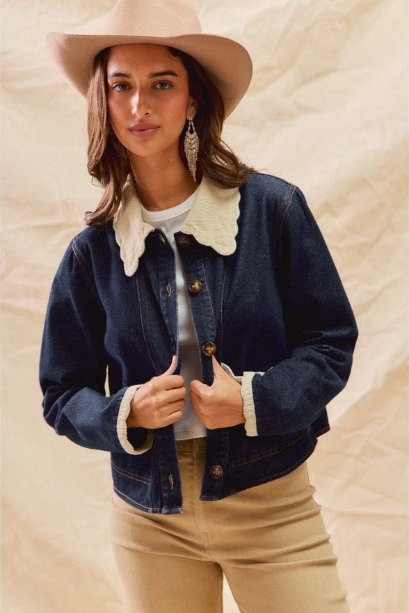 Woman wearing a denim jacket, beige hat, and beige pants against a neutral background