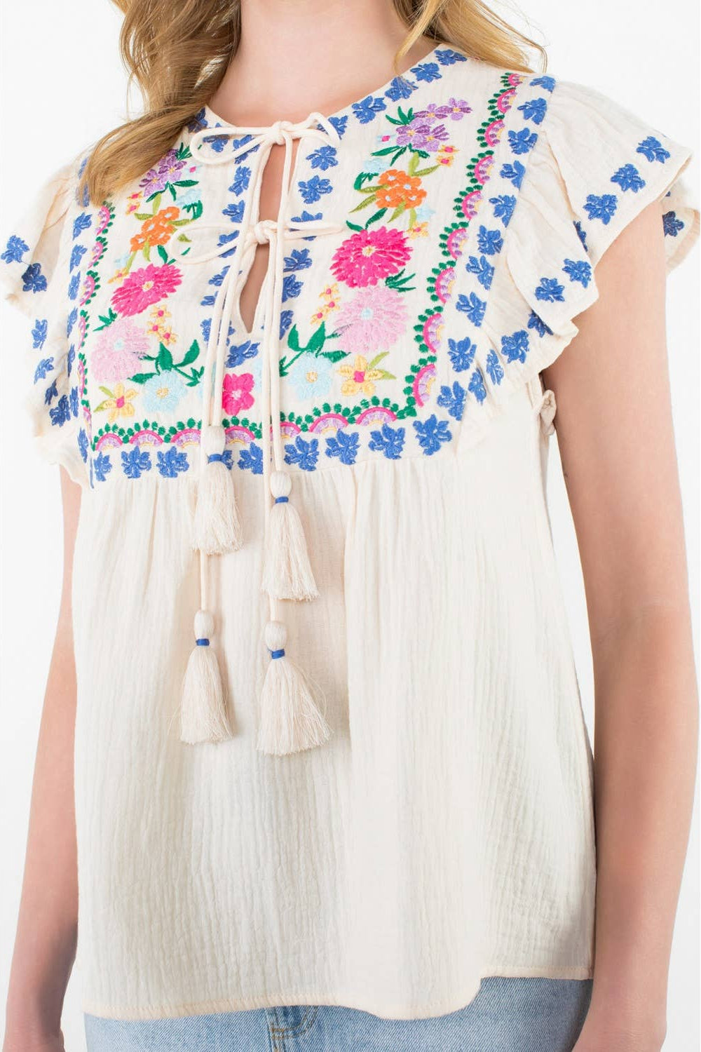 White blouse with colorful floral embroidery on a white background