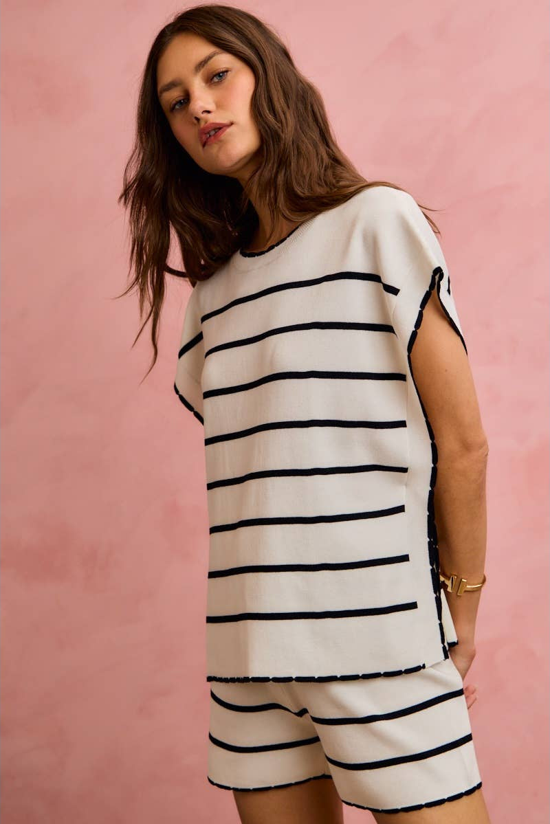 Woman wearing a black and white striped dress against a pink background