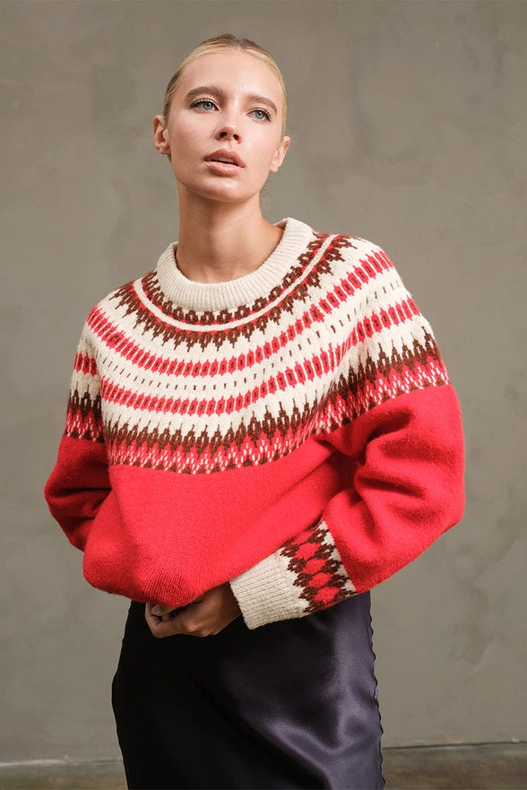 Woman wearing a red and white patterned sweater against a plain background