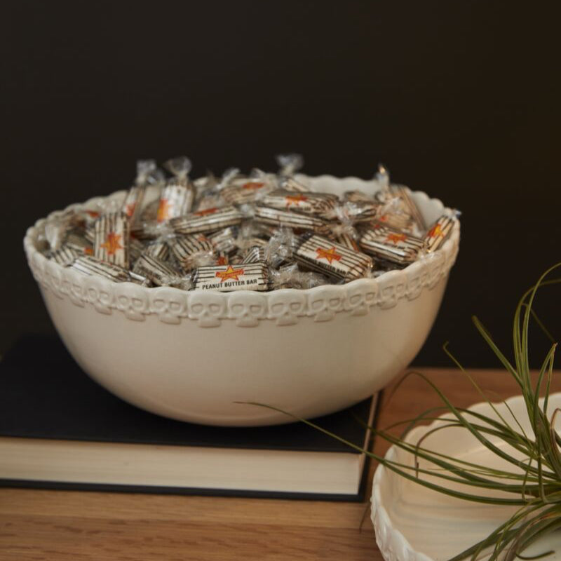 White bowl filled with small packets on a wooden surface with a dark background