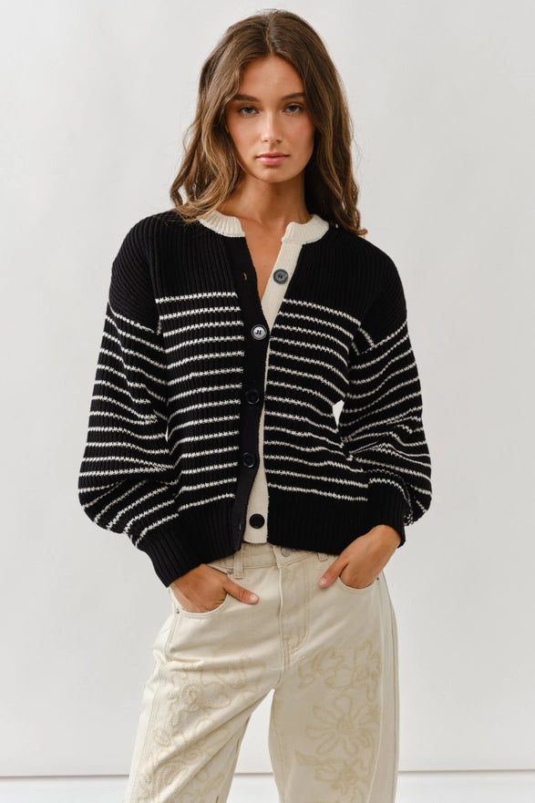 Woman wearing a black and white striped cardigan against a plain background