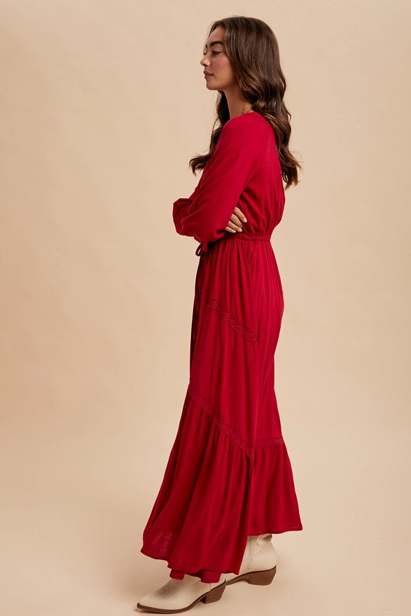 Woman wearing a cherry color maxi dress with long sleeves on plain background