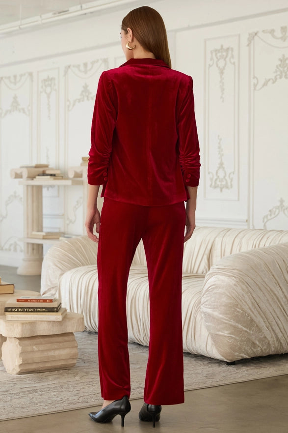 Woman in a red velvet suit standing in a stylish room with decor elements.