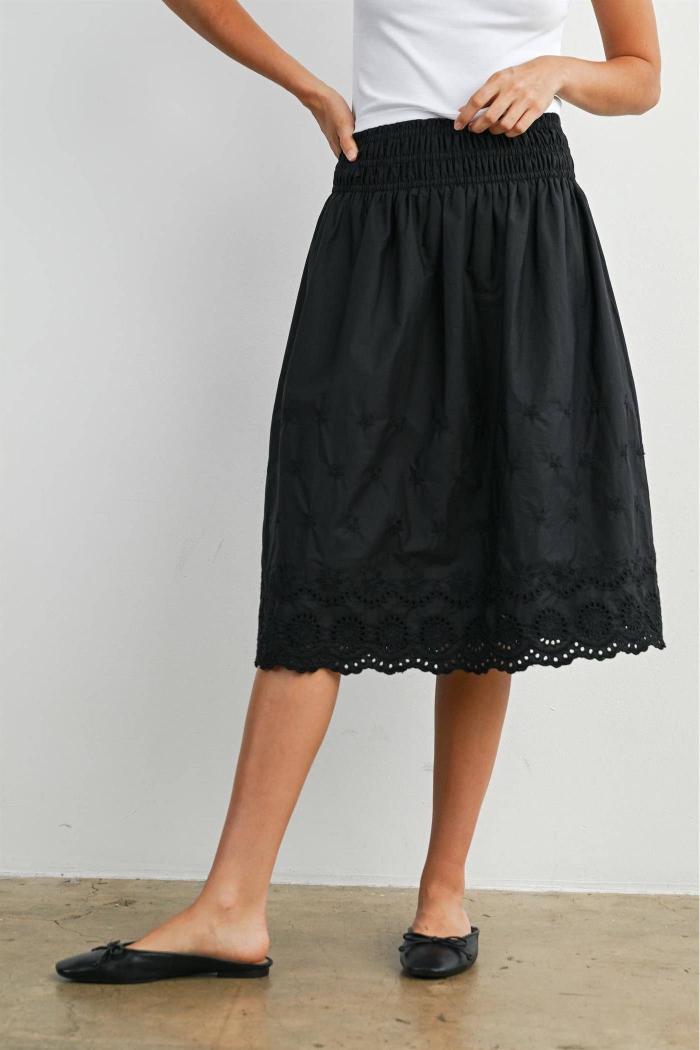 Person wearing a black lace skirt with a plain background