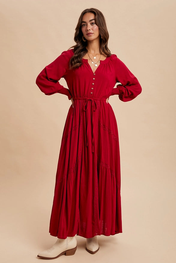 Woman wearing a cherry color maxi dress with long sleeves on plain background