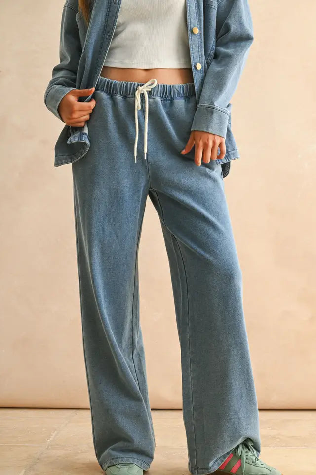 Person wearing a blue denim outfit with a beige background