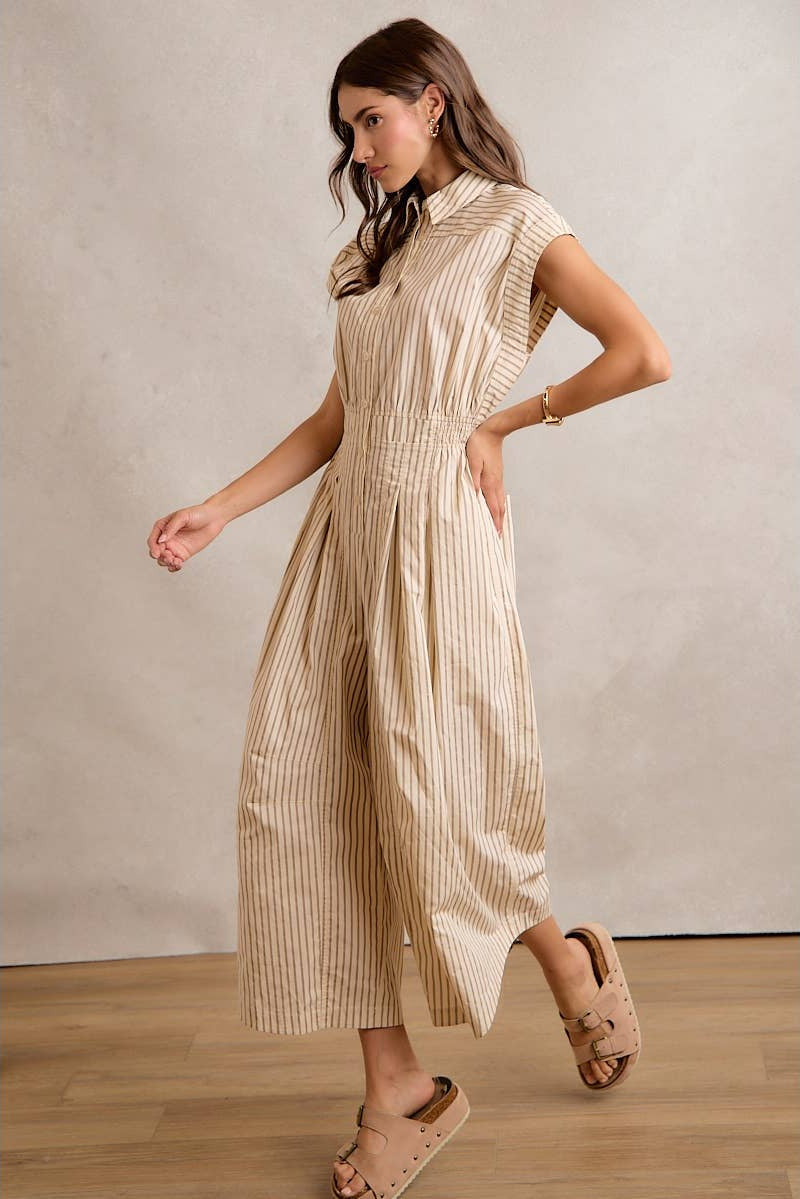 Woman wearing a beige and white striped dress against a plain background