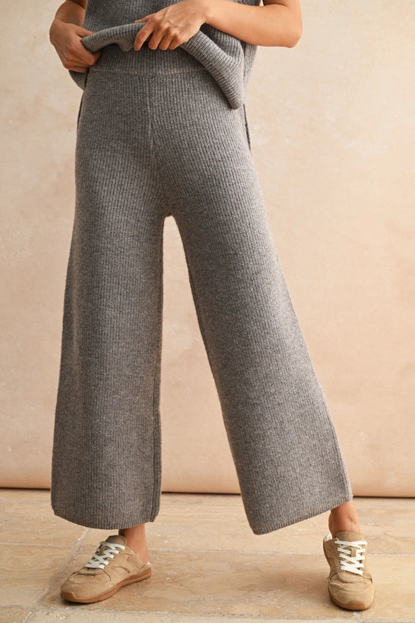 Person wearing gray ribbed knit pants with a beige background